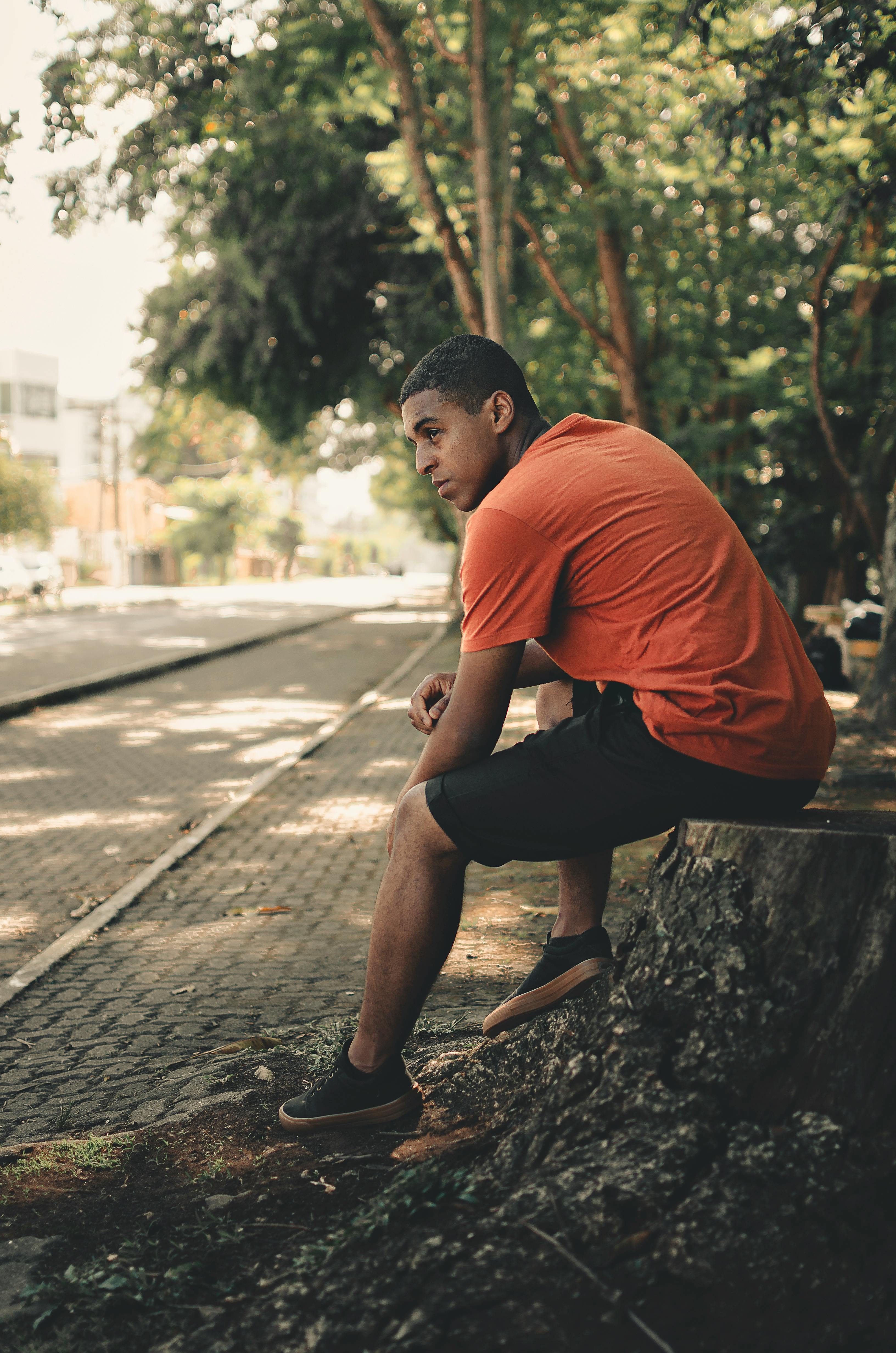 man wearing orange crew neck shirt and black cargo shorts