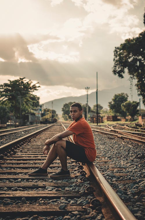 Man Sitting on Railroad during Day