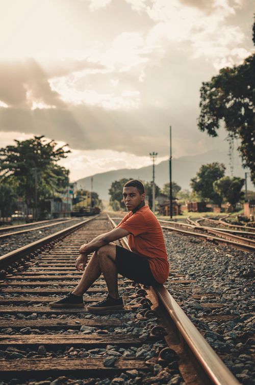 Free Man in casual clothing sitting on railway tracks during sunset in Resende, Brazil. Stock Photo