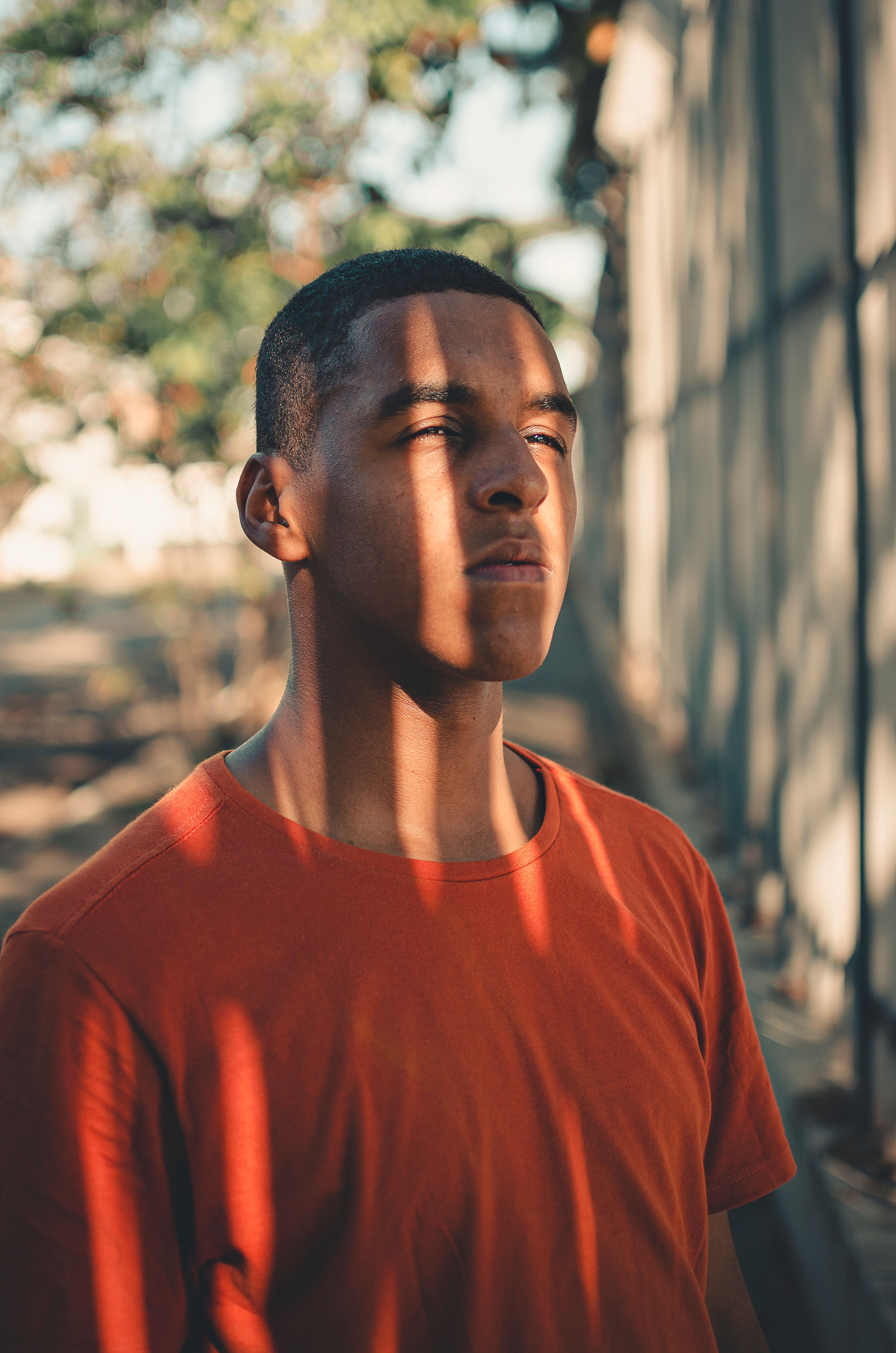 Serious young man in shadows, Resende, Brazil, basking in sunlight outdoors.