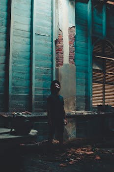 一名男子站在一栋废弃的宏伟建筑里，在戏剧性的灯光下向上仰望