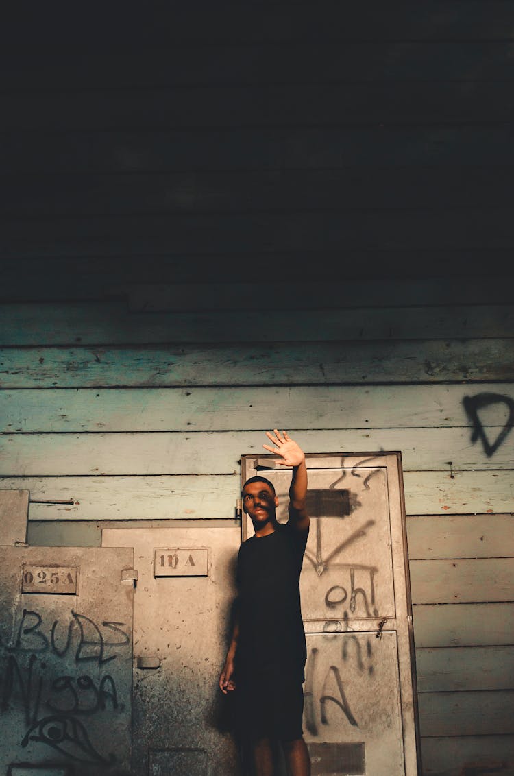 Man Standing Near Wooden Wall While Raising His Arm