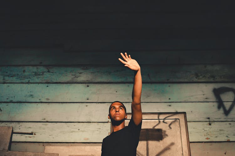 Man Raising His Left Hand Beside Wall