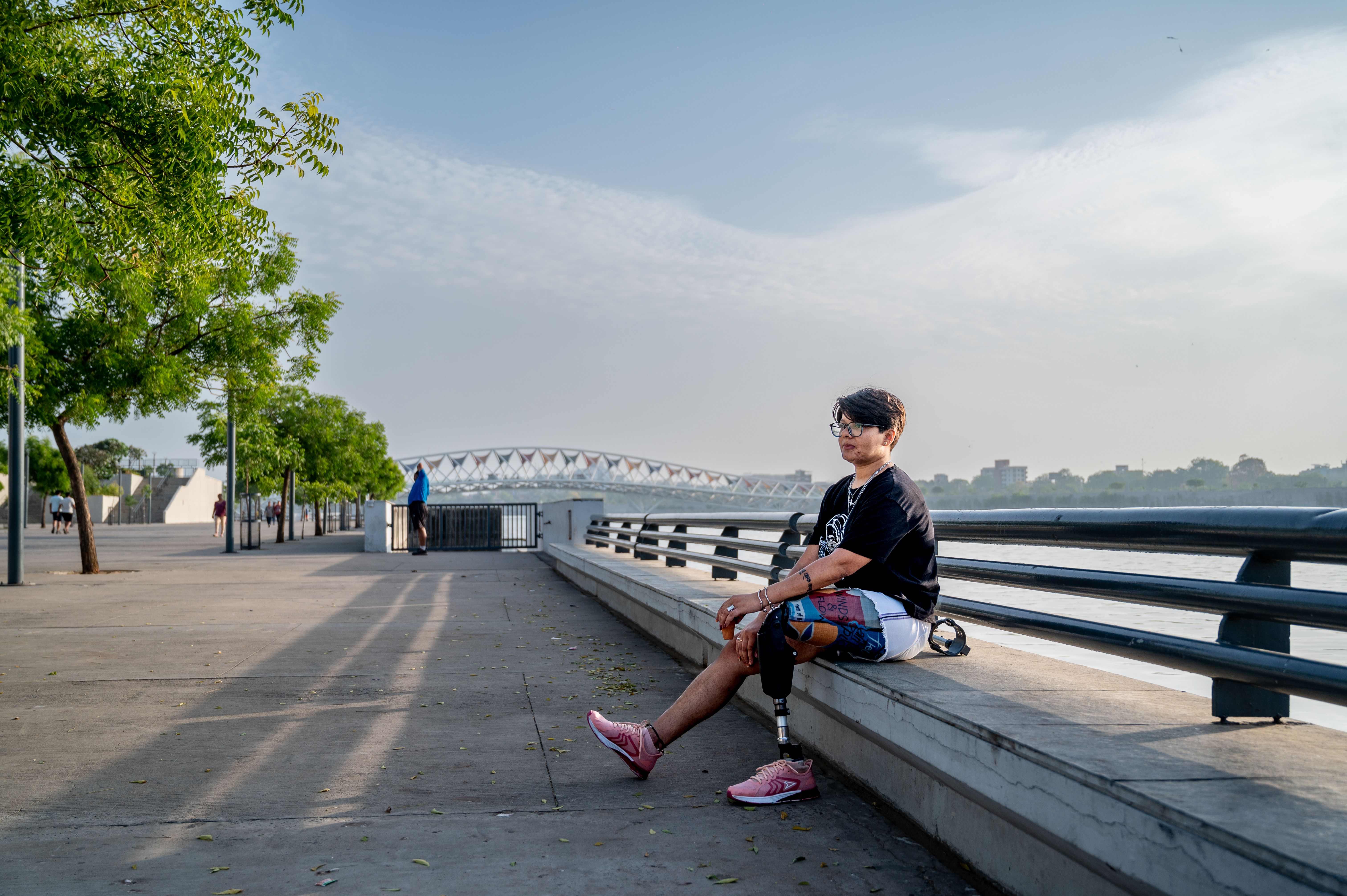 A person with a prosthetic leg relaxes by the riverfront in Ahmedabad, India, on a sunny day.