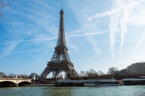 Free Iconic view of the Eiffel Tower by the Seine River under a blue sky in Paris, France. Stock Photo