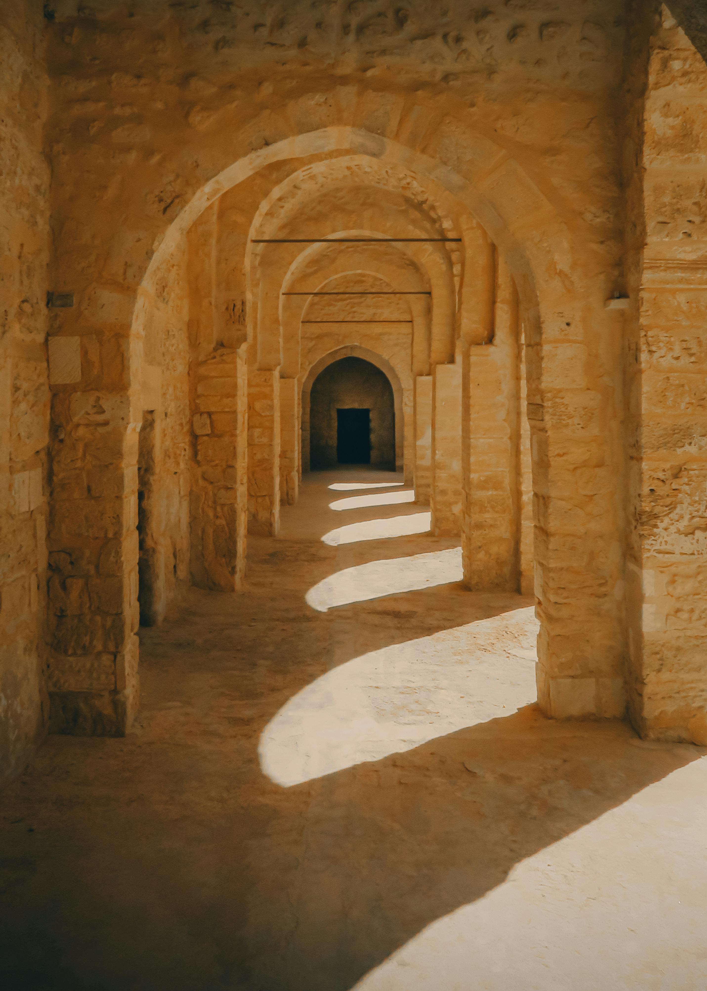 Explore the historic charm and architectural beauty of an ancient Tunisian castle through its sunlit arched corridor.