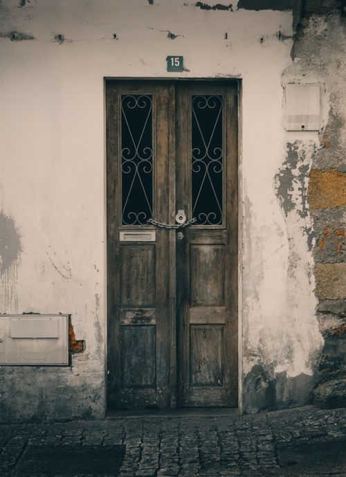 Free Rustic wooden door in a weathered building facade in Portugal, showcasing vintage architecture. Stock Photo