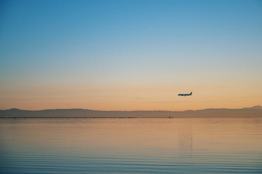 日落时分，飞机飞越平静海面的宁静场景