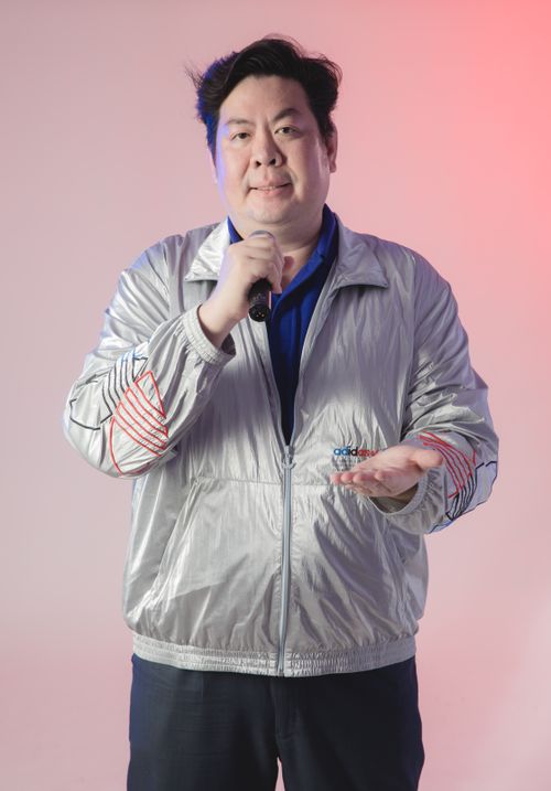Free Adult male in silver jacket with microphone, neutral background, studio lighting. Stock Photo