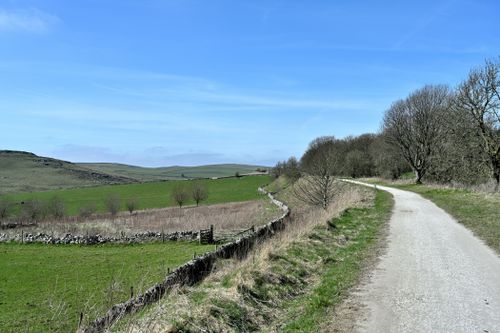 Free A winding gravel path through lush countryside under a clear blue sky. Stock Photo