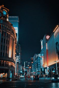 Experience the vibrant nightlife of Ginza, Tokyo, in this stunning street view illuminated by towering neon lights.