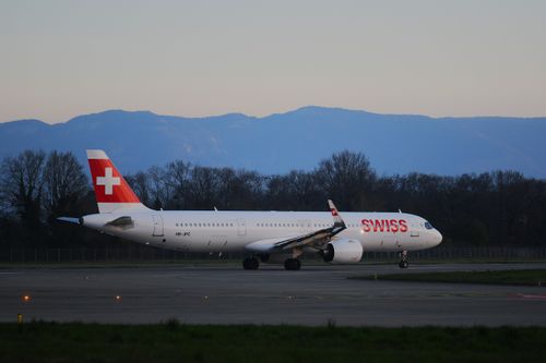 Free A Swiss Airbus A320 taxiing during sunrise at Genève Airport with serene mountain backdrop. Stock Photo