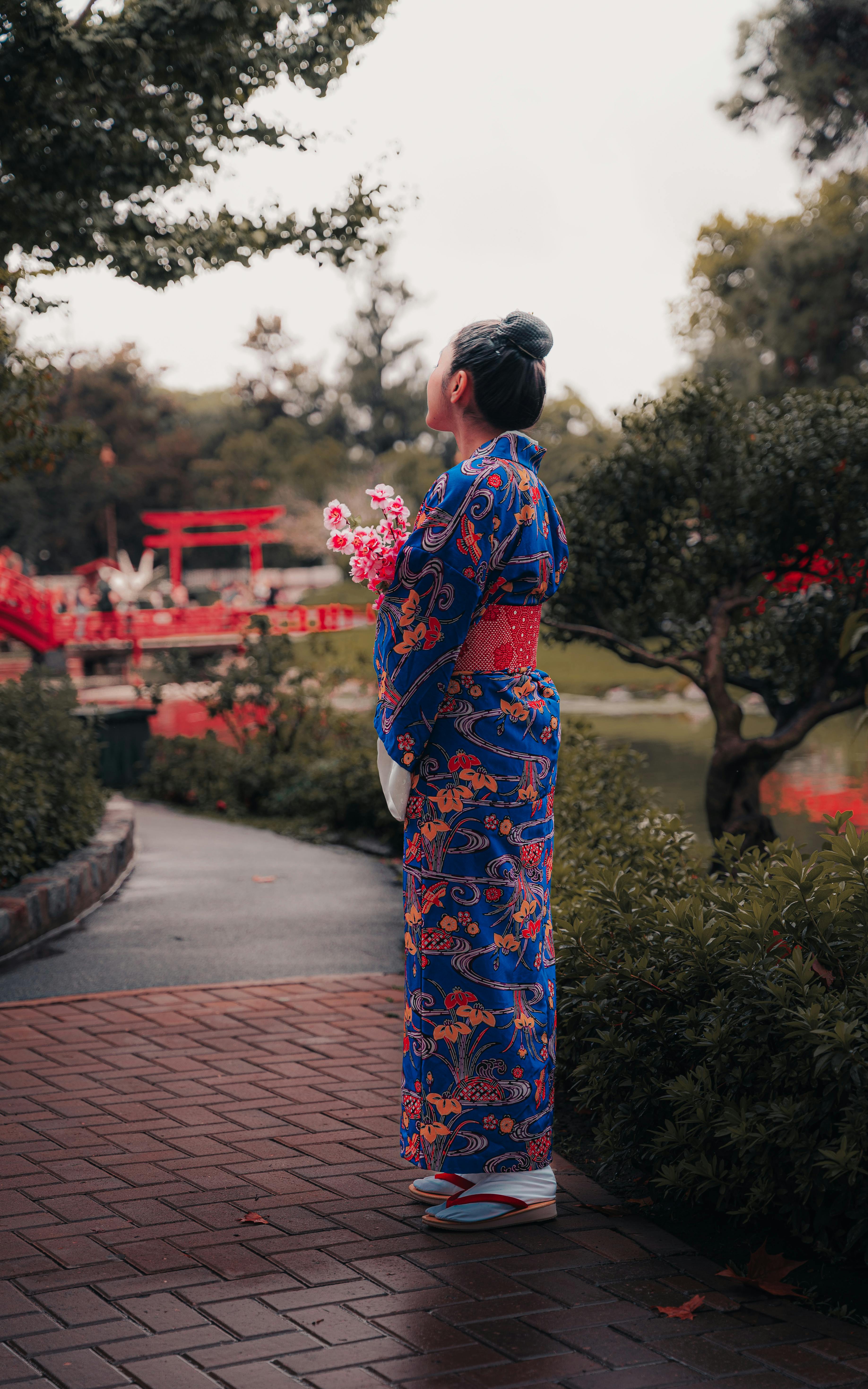 A woman in a blue kimono admires a serene Japanese garden, embracing tradition and nature.