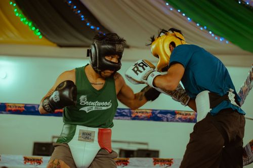 Free Intense boxing match between two athletes in a well-lit indoor arena with vibrant energy. Stock Photo