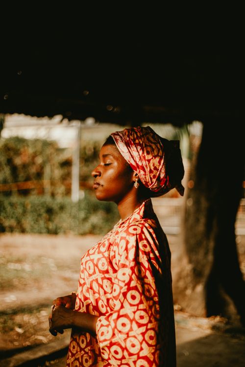 Free Portrait of a woman in traditional African dress and headwrap, standing outdoors. Stock Photo