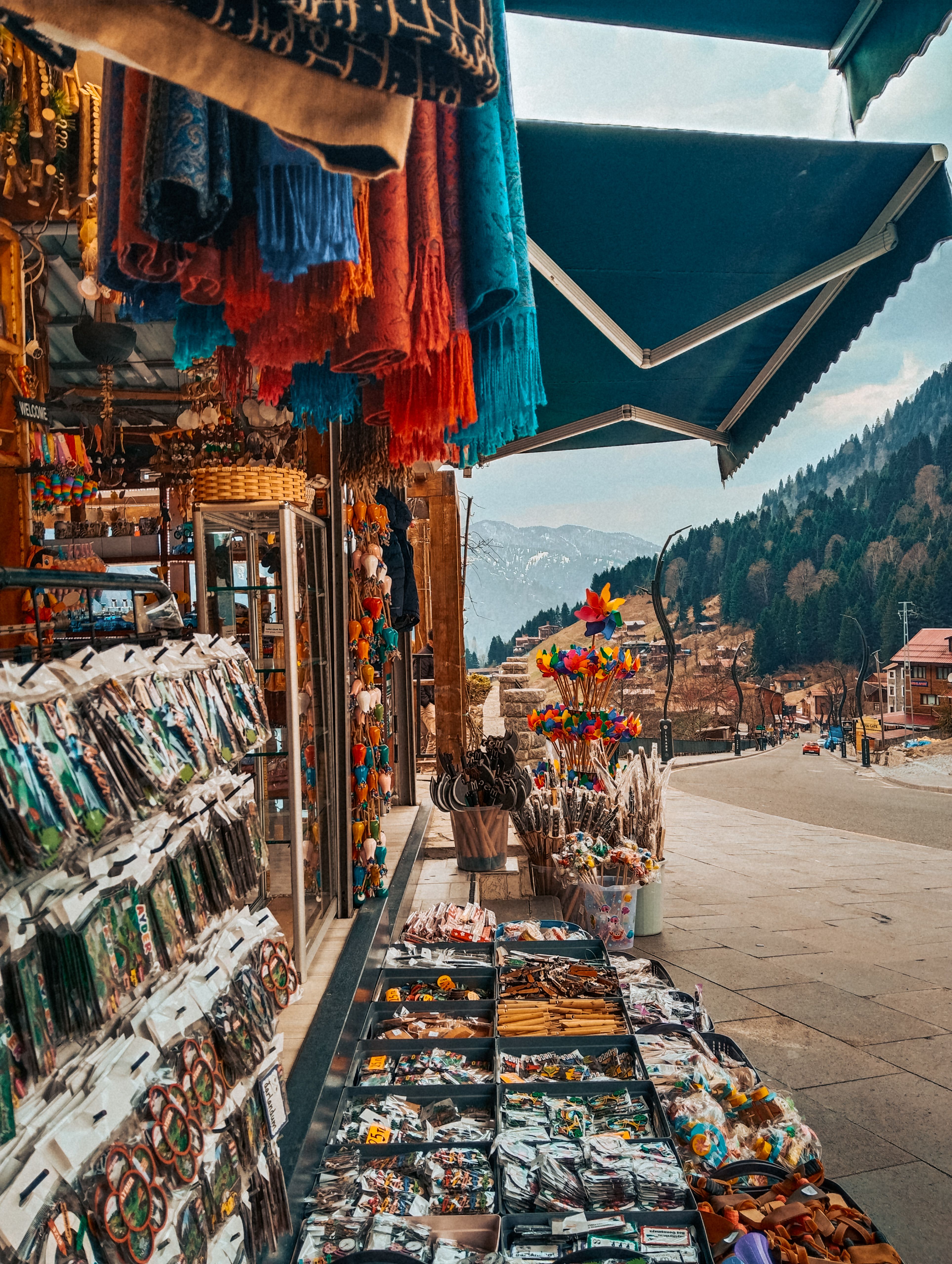 A vibrant outdoor souvenirs market in a picturesque mountain village, showcasing handcrafted items under a clear sky.