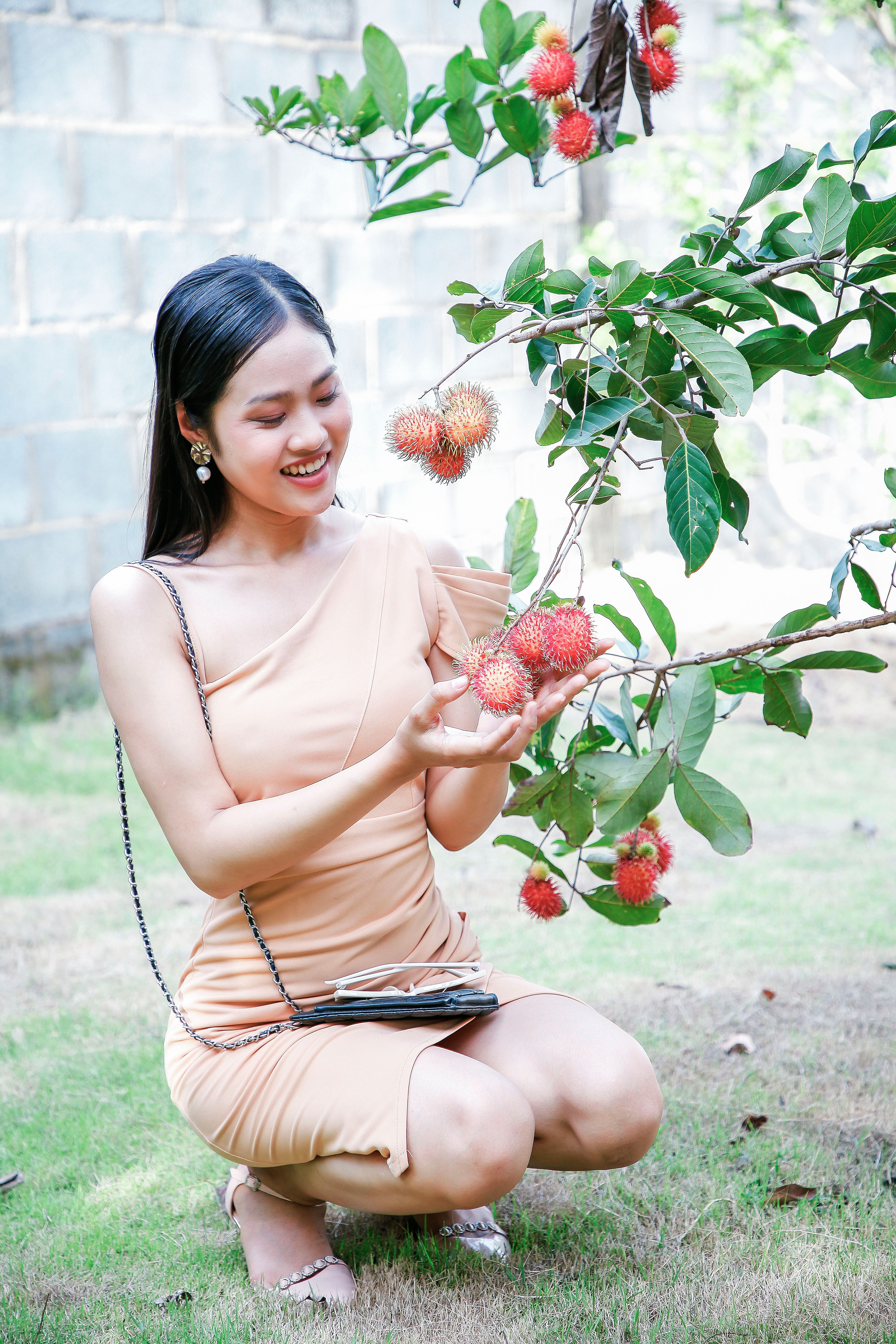 Young Woman Smiling with Fresh Rambutan Fruit Outdoors · Free Stock Photo