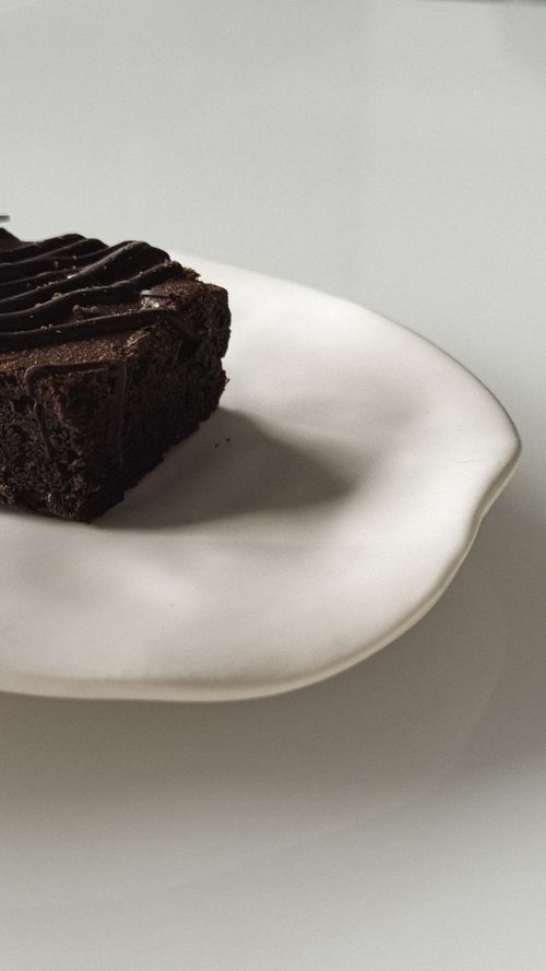 Free A rich chocolate brownie slice served on a modern white ceramic plate. Stock Photo