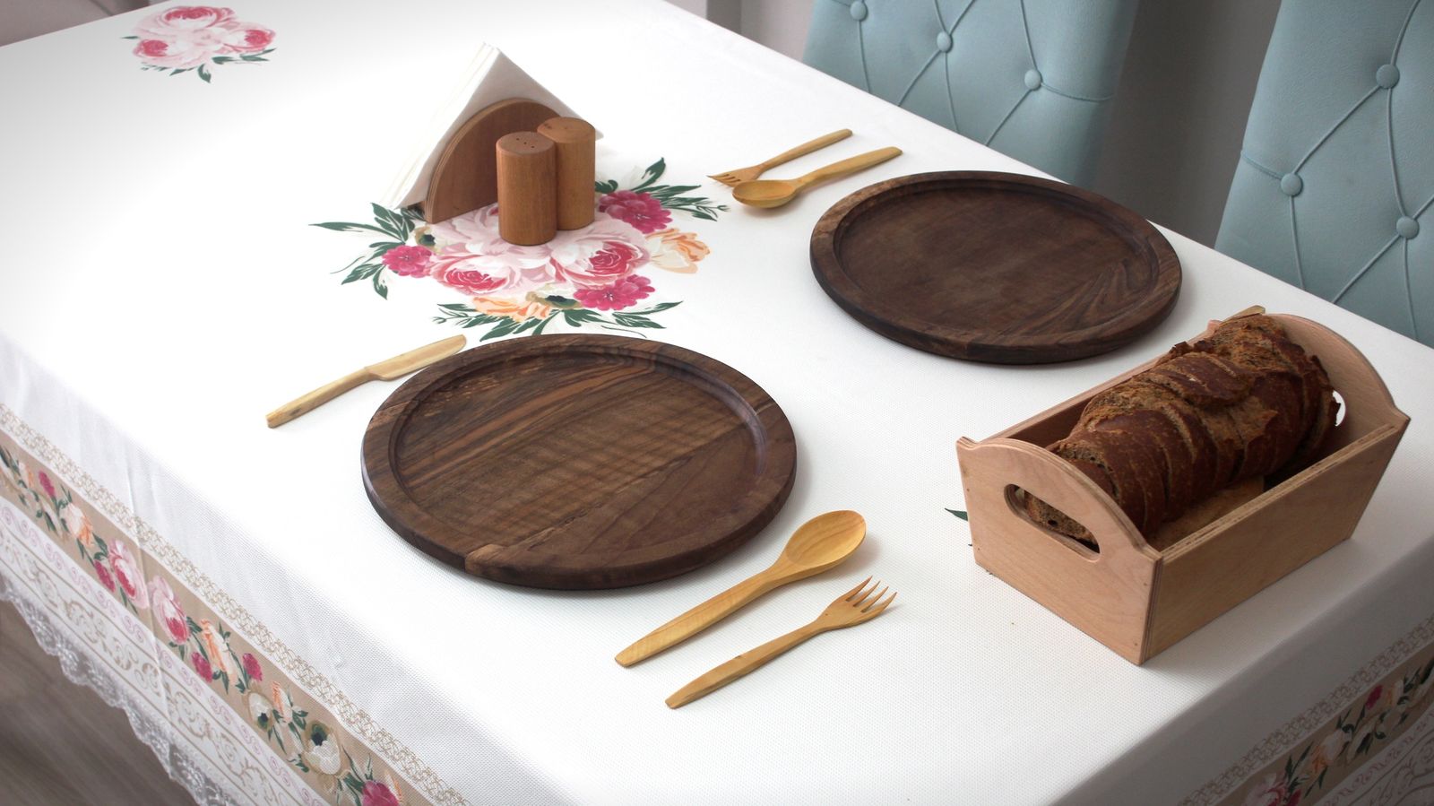 Chic table setup featuring wooden platters, utensils, and floral tablecloth decor.