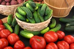 Colorful assortment of fresh vegetables including tomatoes, cucumbers, and sweet potatoes at a market.