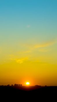 Capture of a vibrant sunset over a silhouetted city skyline with clear skies.