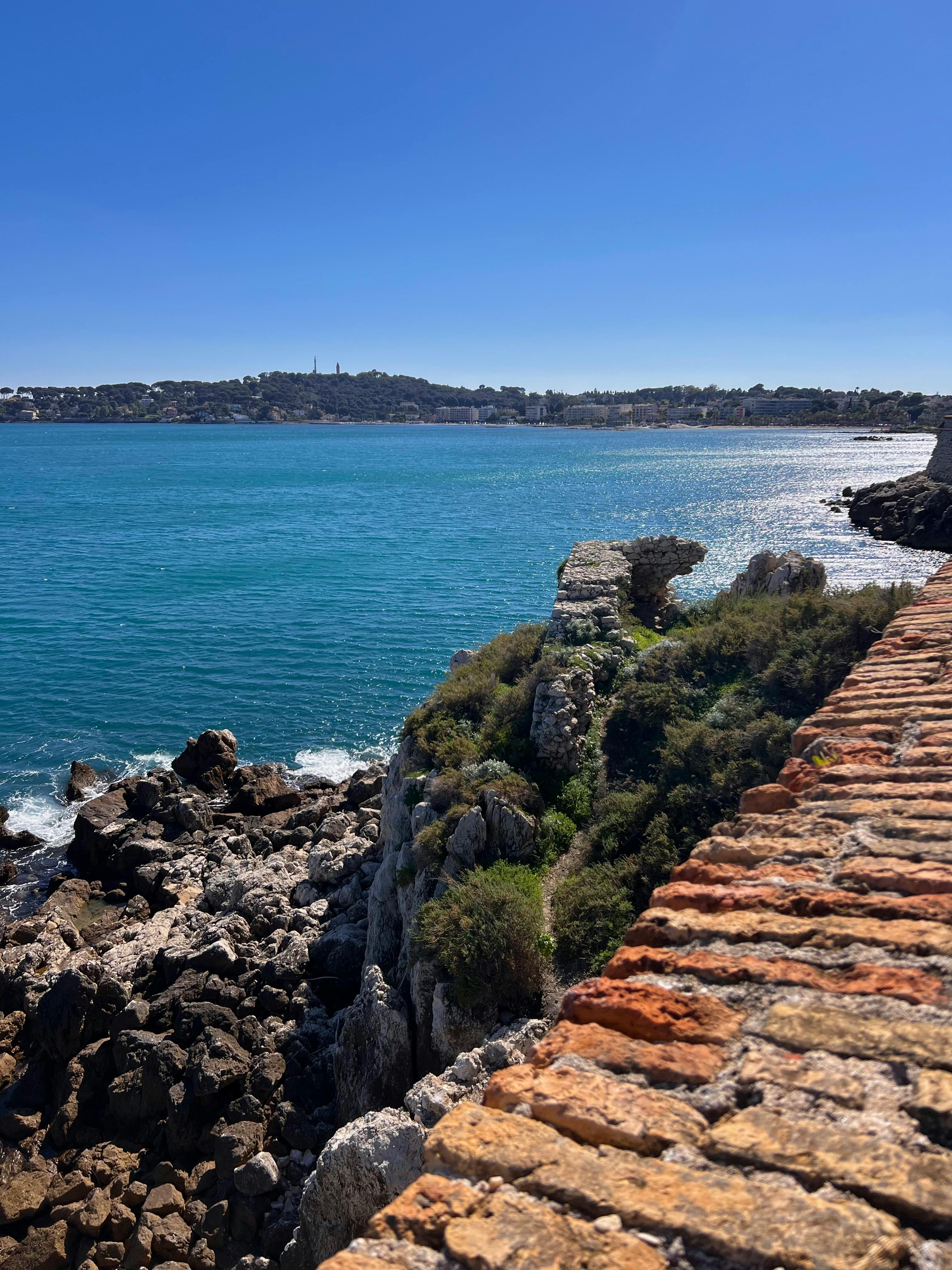 Breathtaking coastal view of the French Riviera from Antibes, featuring clear blue water and rocky shoreline.