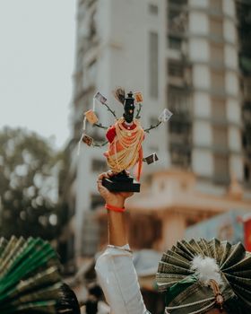 Colorful Indian festival celebration with decorative idol held high by participants.