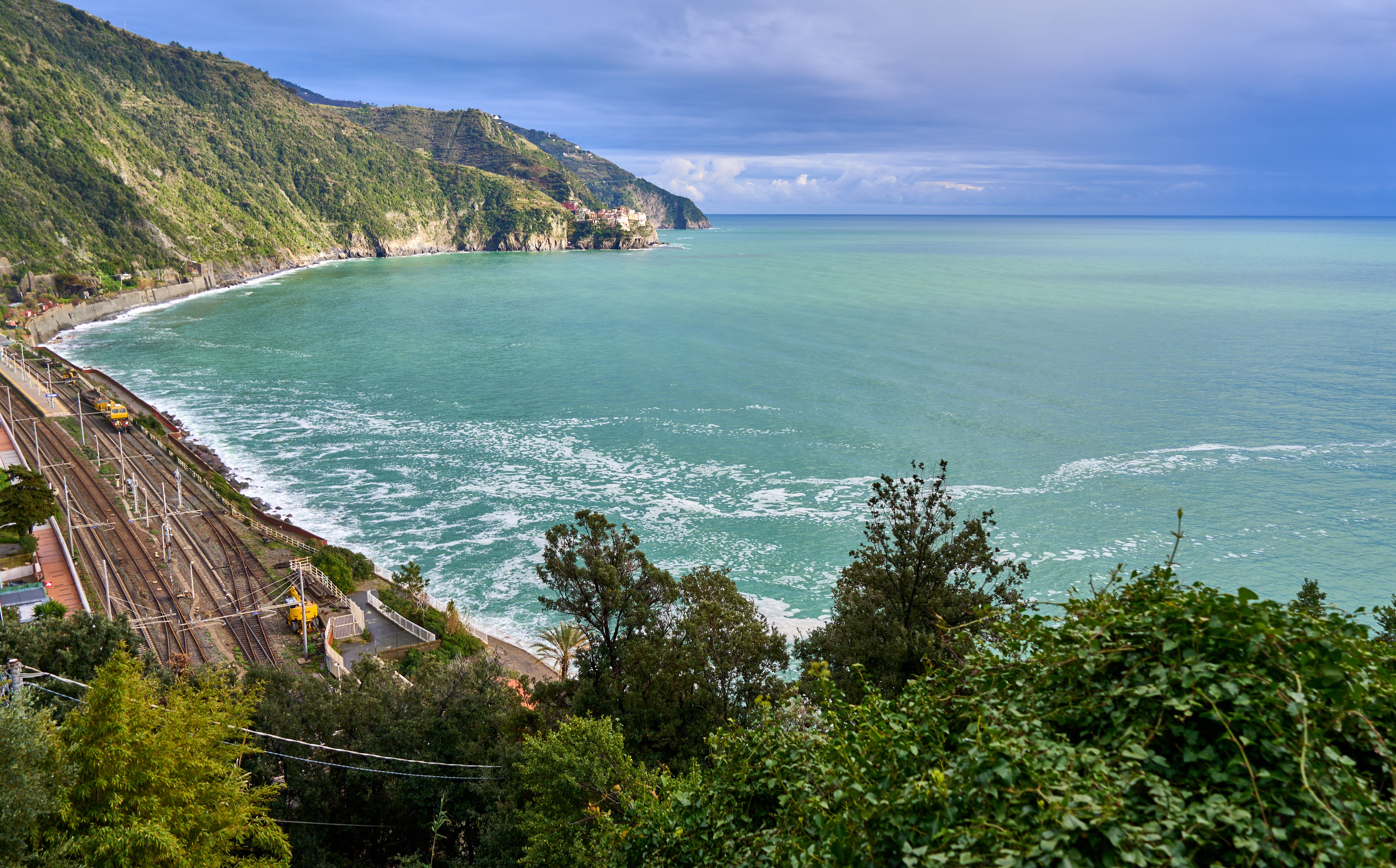 A breathtaking view of the Ligurian coast featuring lush greenery, azure waters, and a railway line along the shoreline. A breathtaking view of the Ligurian coast featuring lush greenery, azure waters, and a railway line along the shoreline.
