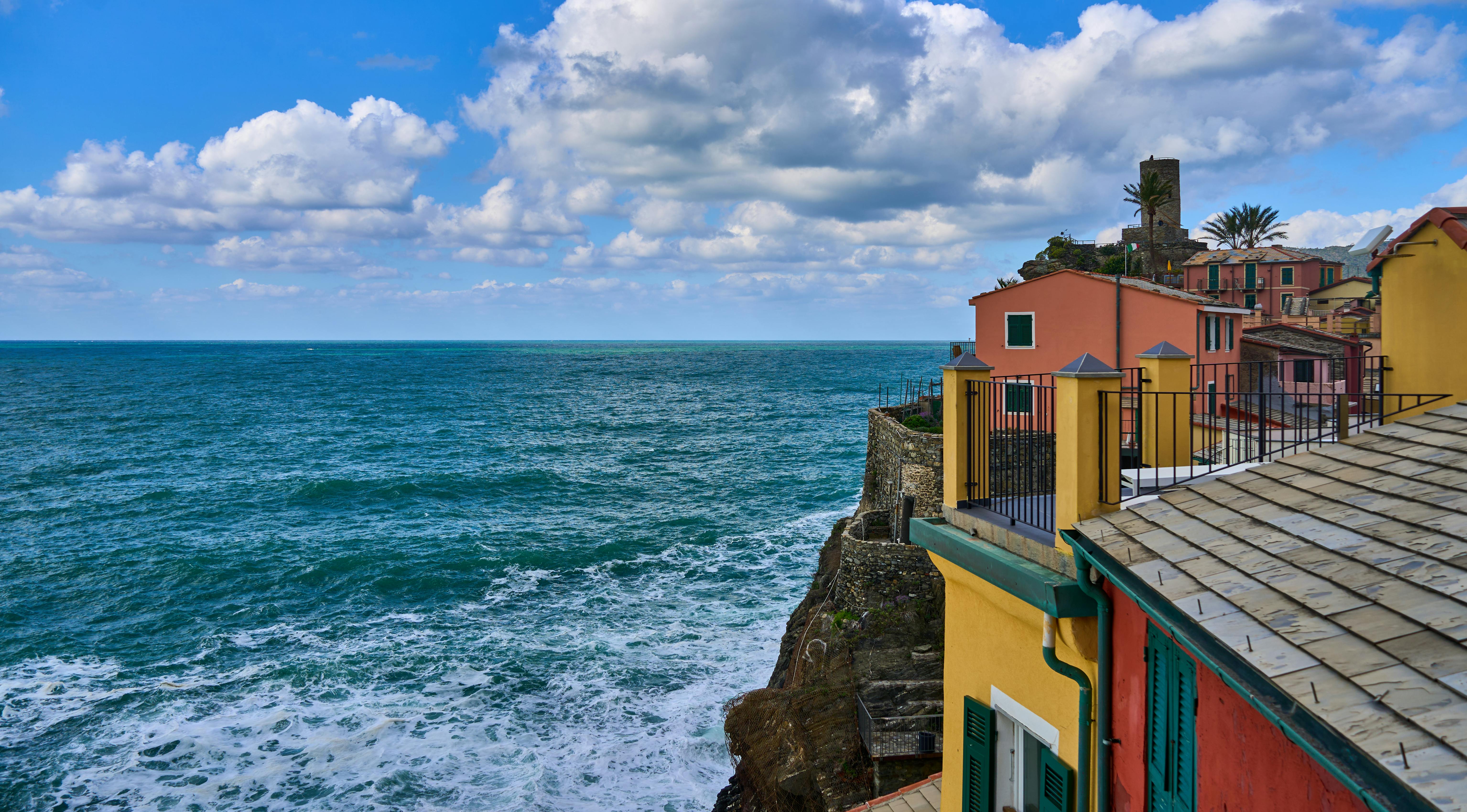 Scenic view of vibrant houses along the picturesque coastline with blue ocean waves under a cloudy sky.