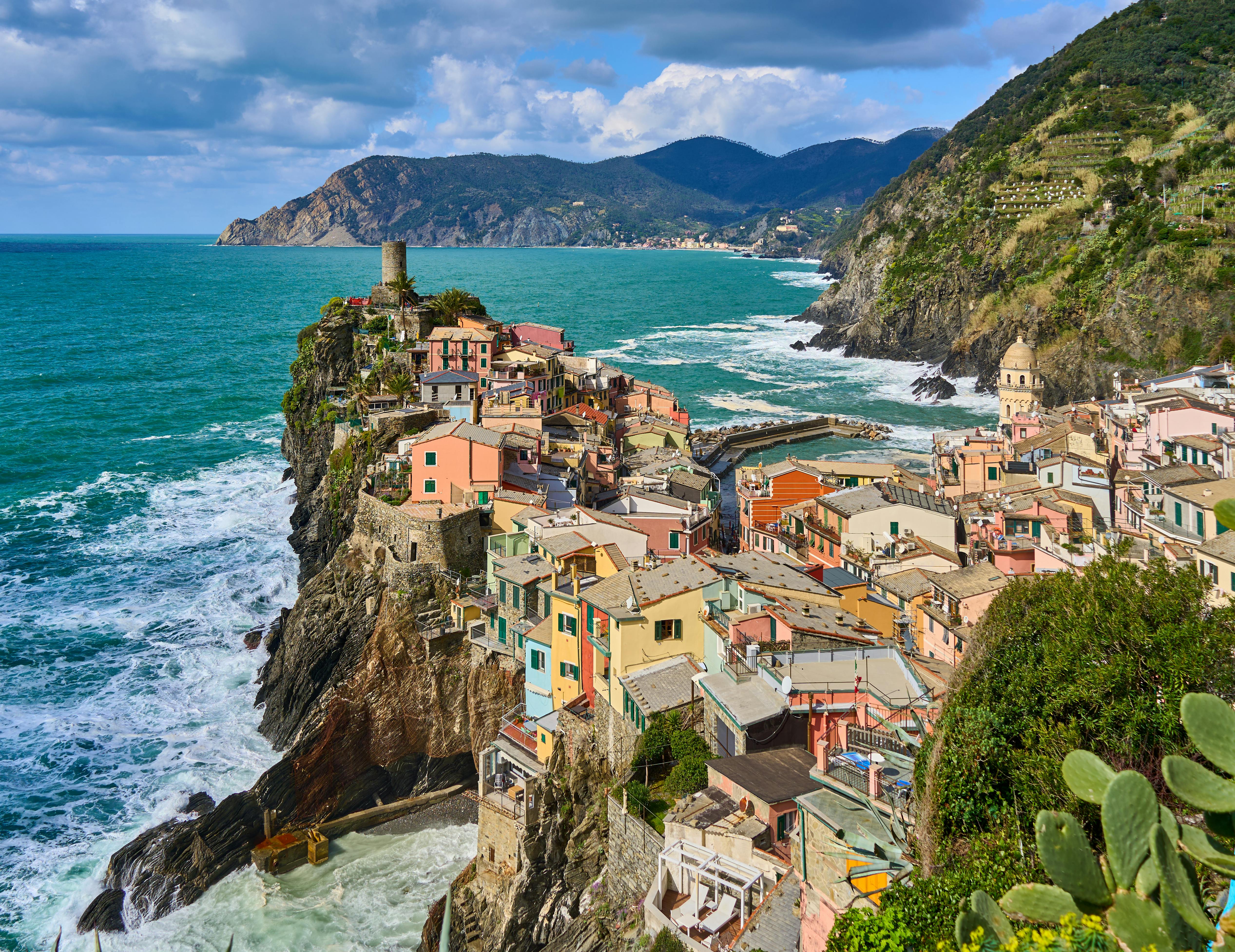 aerial view of colorful houses on a steep cliff by a turquoise sea, Italy