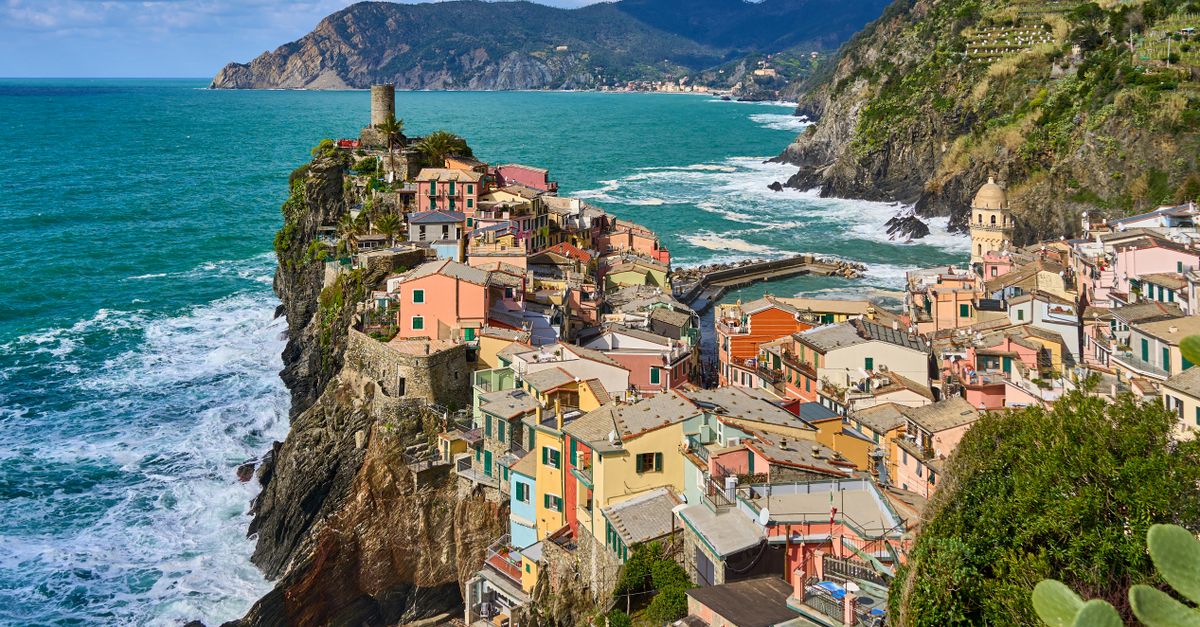 aerial view of colorful houses on a steep cliff by a turquoise sea, Italy