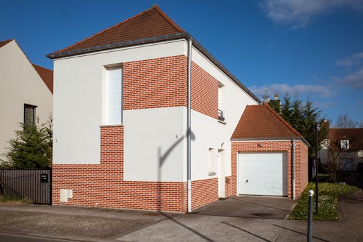 A contemporary suburban home with red brick and white facade in a sunny neighborhood setting.