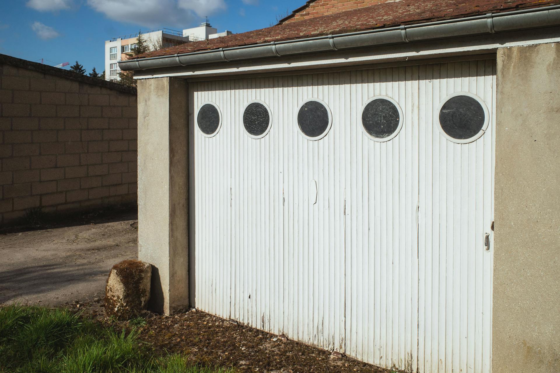 White garage door with circular windows in a residential area of Compiègne, France.