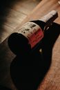A Japanese sake bottle lies on a wooden surface, lit dramatically for a moody effect.