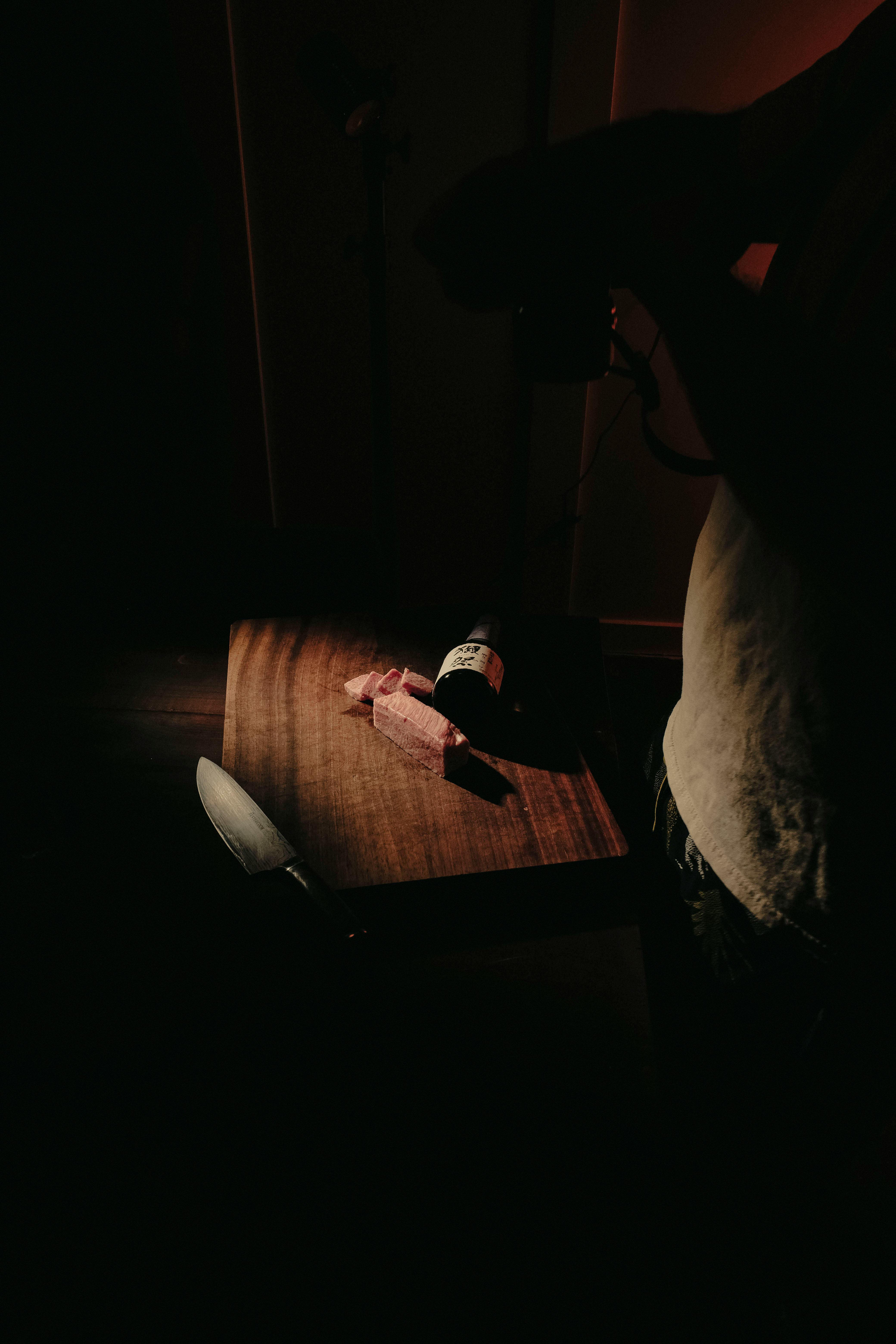 Gratuit Scenă de bucătărie moody cu sticla de vin și cuțit de feliere pe masă de lemn. Fotografie de stoc