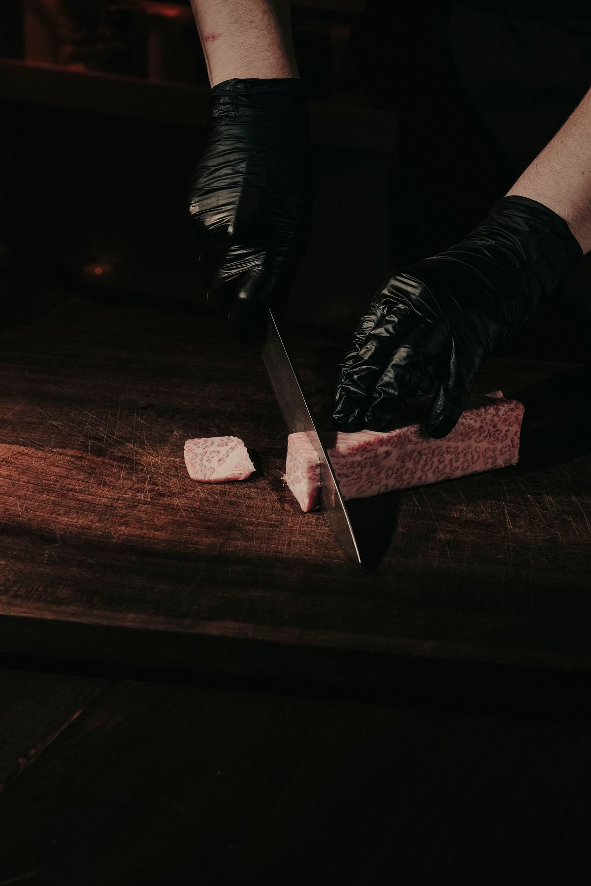Chef's hands slicing premium Japanese wagyu beef on a wooden board