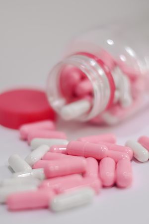 An open bottle spilling pink and white capsules — photo by Deise Elen on Pexels