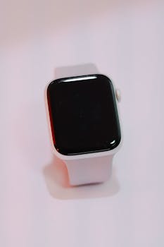 Close-up of a white smartwatch with a blank screen on a soft, light background.