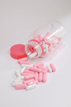 Close-up of pink and white capsules spilled from a jar, ideal for healthcare themes.