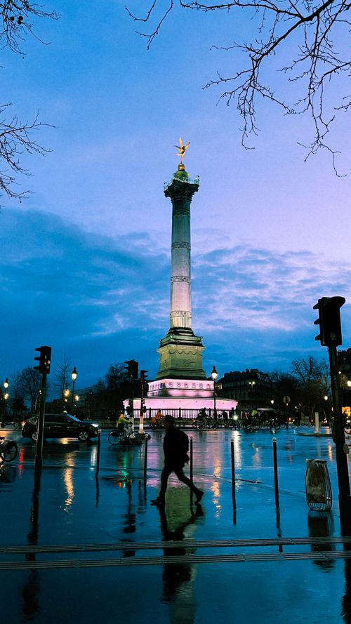 Free A silhouette walks past the illuminated July Column at Place de la Bastille, Paris, during twilight. Stock Photo