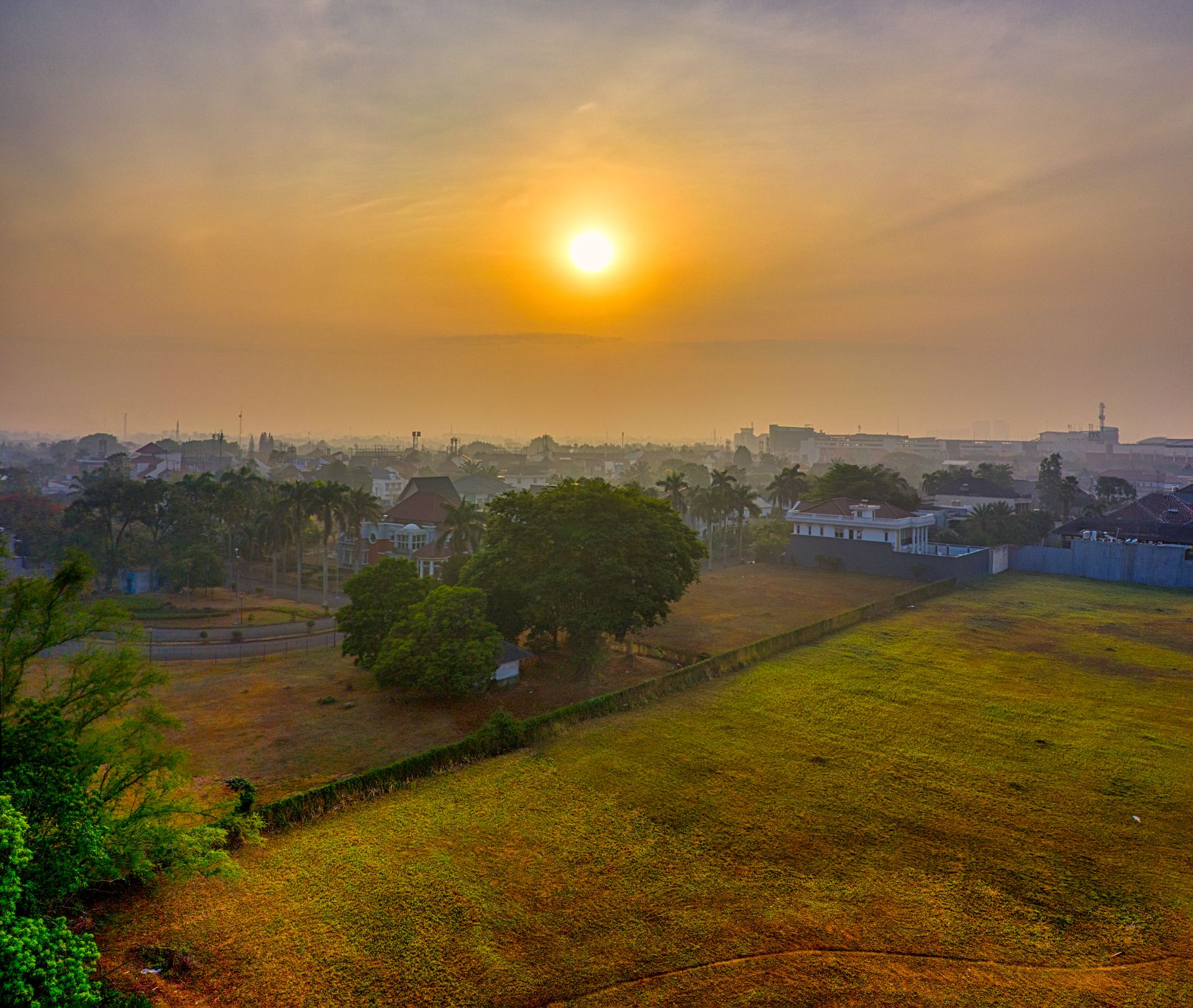 Captivating aerial view of a misty Banten cityscape with the sunrise casting a golden glow.