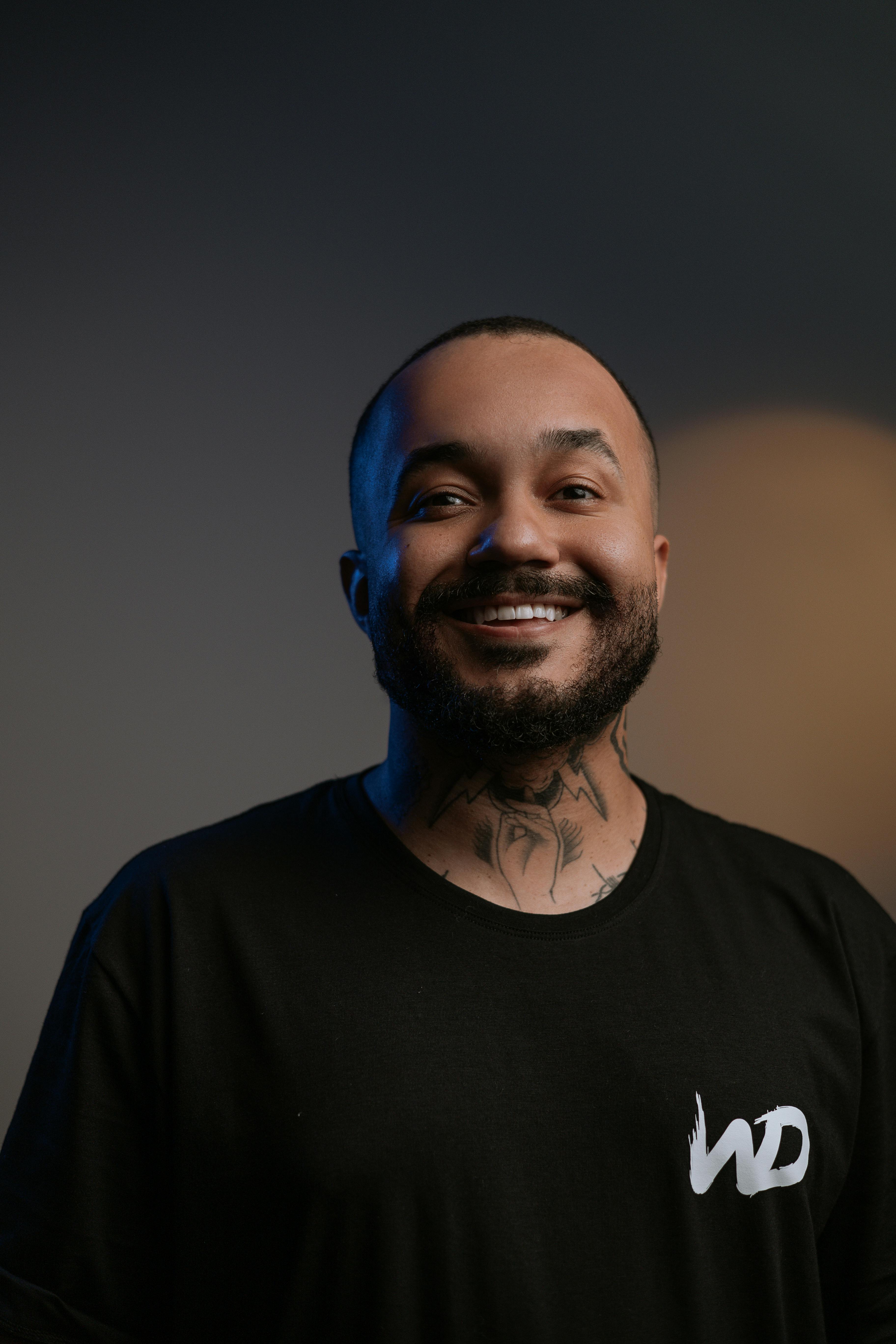 Happy man with beard and tattoo smiling in studio portrait