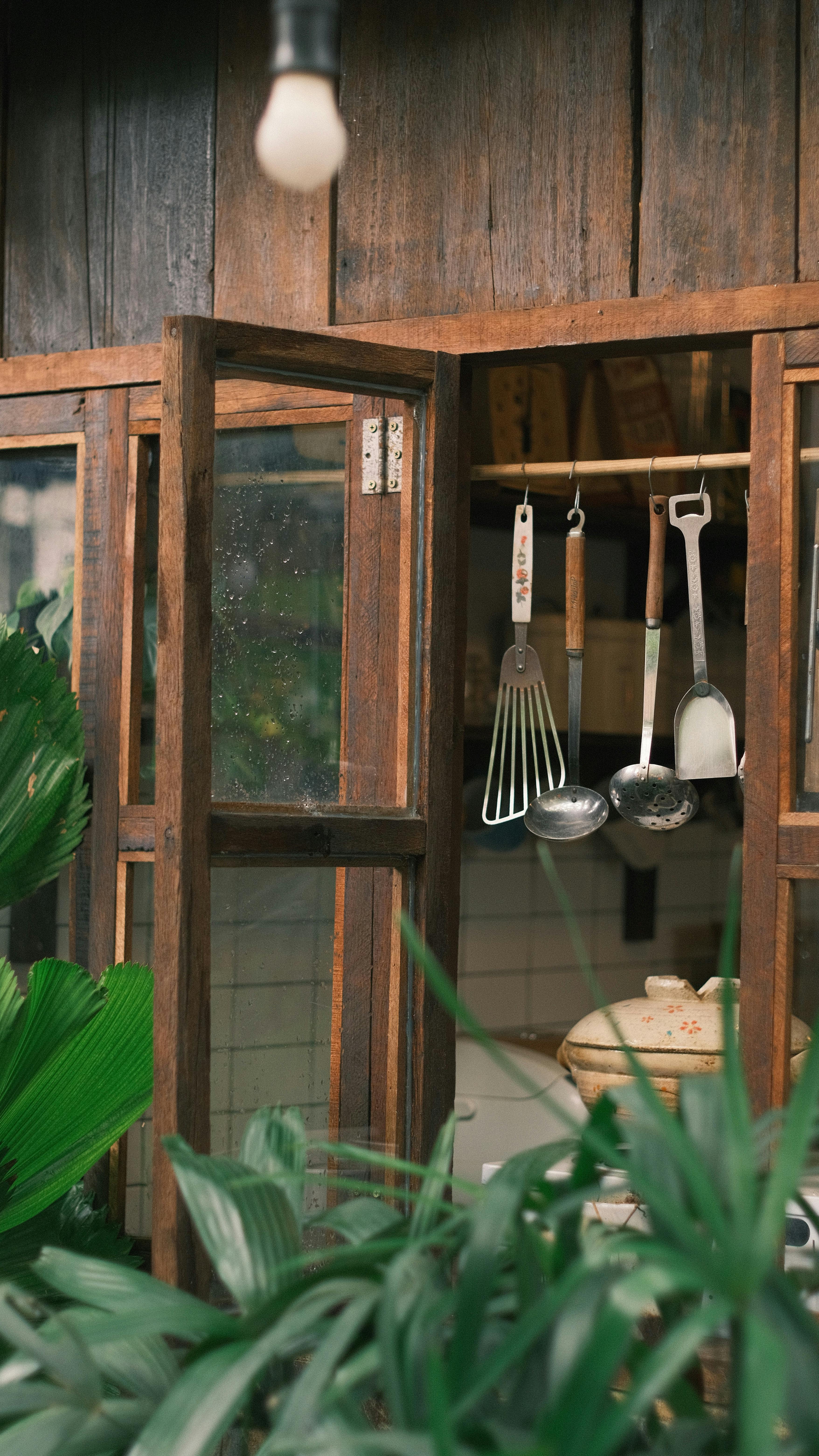 Rustic kitchen setup with wooden cabinets and kitchen utensils outdoors.