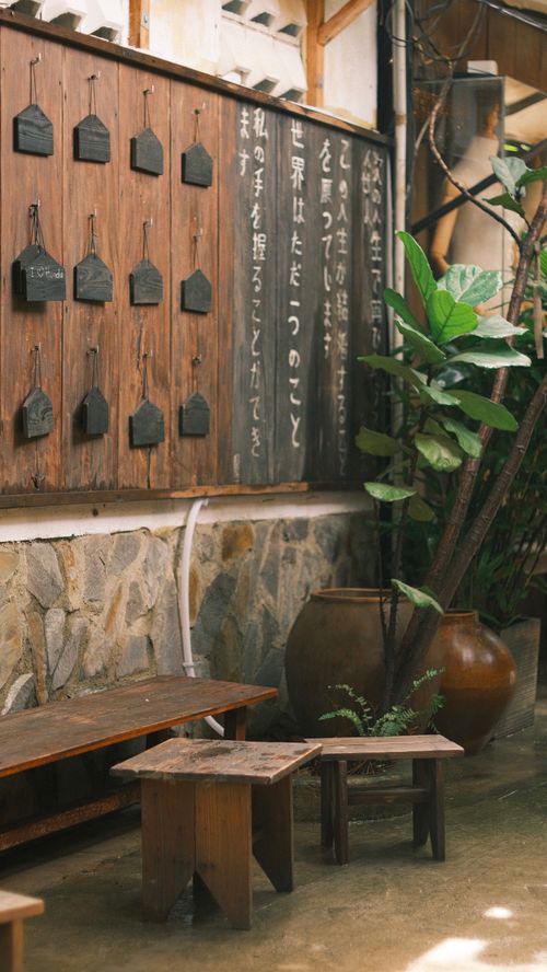 Free Charming outdoor cafe with rustic benches and a decorative wooden wall adorned with text. Stock Photo