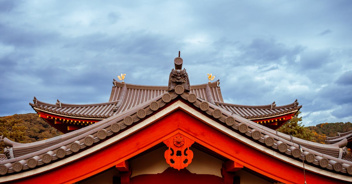 Beautiful shot of a traditional Japanese temple roof with intricate design under a cloudy sky. Beautiful shot of a traditional Japanese temple roof with intricate design under a cloudy sky.