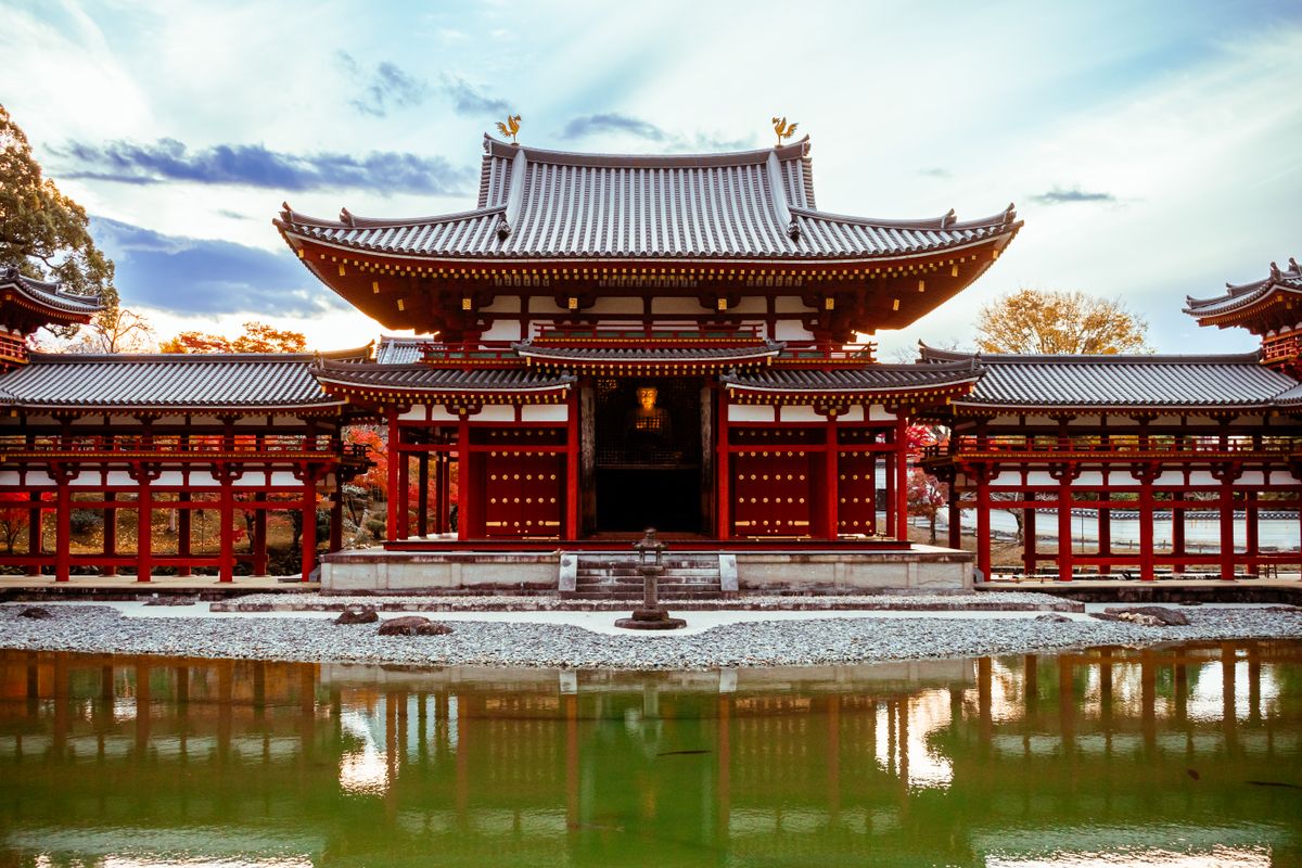 Historic Pure Land style Japanese temple with autumn foliage reflected in a pond, similar in spirit to Hiraizumi's Heian-era halls