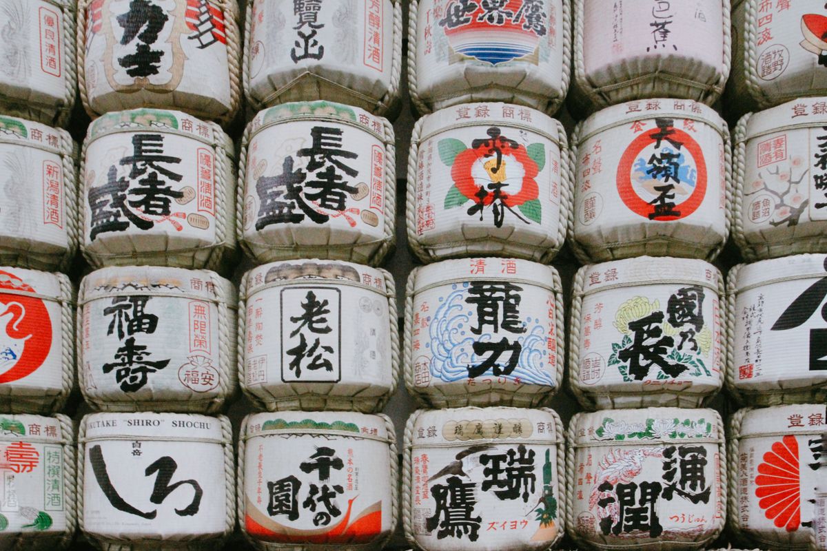 Traditional Japanese sake barrels stacked with kanji labels — kazaridaru decorative barrels at a sake display
