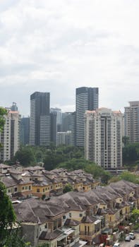 Cityscape featuring modern skyscrapers and suburban houses on a cloudy day.