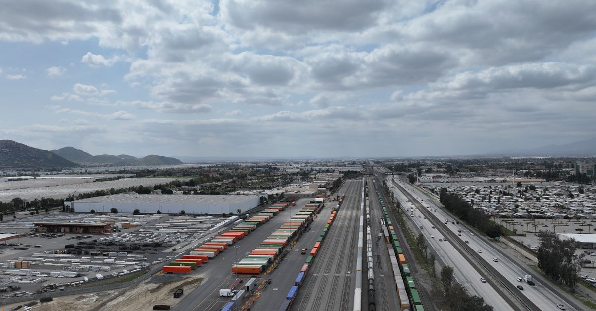 Aerial shot of a busy rail yard and logistics hub in California showcasing freight trains and transportation infrastructure.