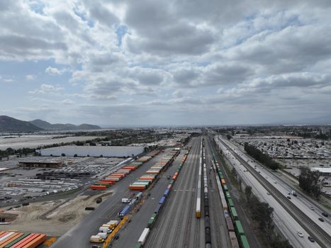 Aerial shot of a busy rail yard and logistics hub in California showcasing freight trains and transportation infrastructure.